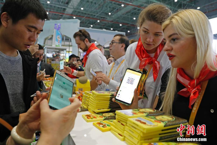 资料图：2018年11月10日，首届中国国际进口博览会食品及农产品展区，参观者扫码支付购买商品。中新社记者 殷立勤 摄
