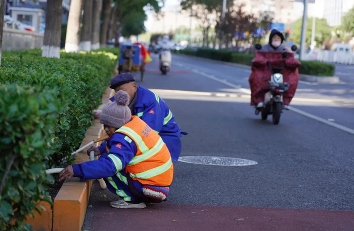 ▲广渠门内大街，园林工人正在为绿化带浇水。