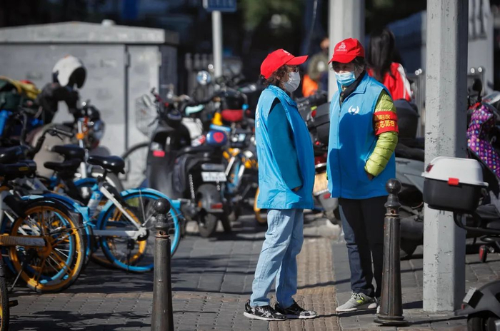 ▲朝阳路，两位志愿者在大风中值守。