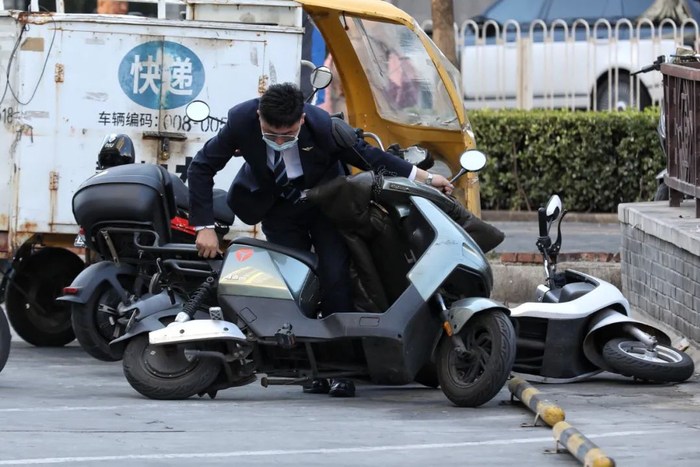 ▲蒲黄榆，一位男士正在扶起被大风吹倒的电动自行车。