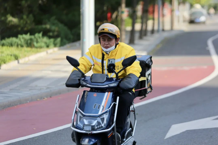 ▲天宫院，外卖员穿着厚外套，在风中忙碌。