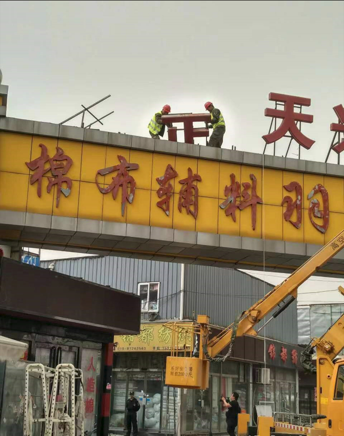 工人在拆除正天兴辅料批发市场的招牌。丰台区供图
