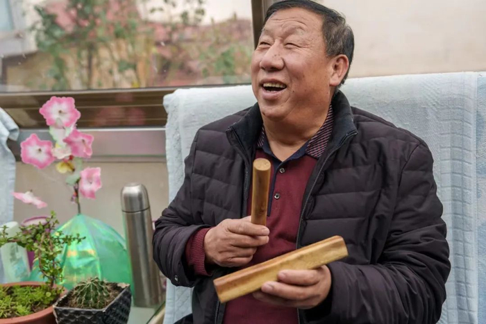 ▲10月26日，王瑞胜在采访间隙拿起村民的乐器梆子，开始互动。新京报记者 王子诚 摄
