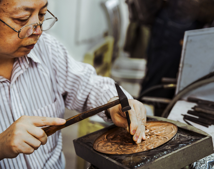 ▲2016年，李建军在錾刻铜盘。受访者供图