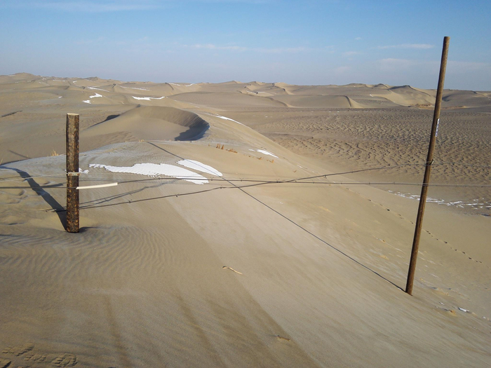 2017年，塔克拉玛干沙漠中被沙子掩埋的电线杆。受访者供图