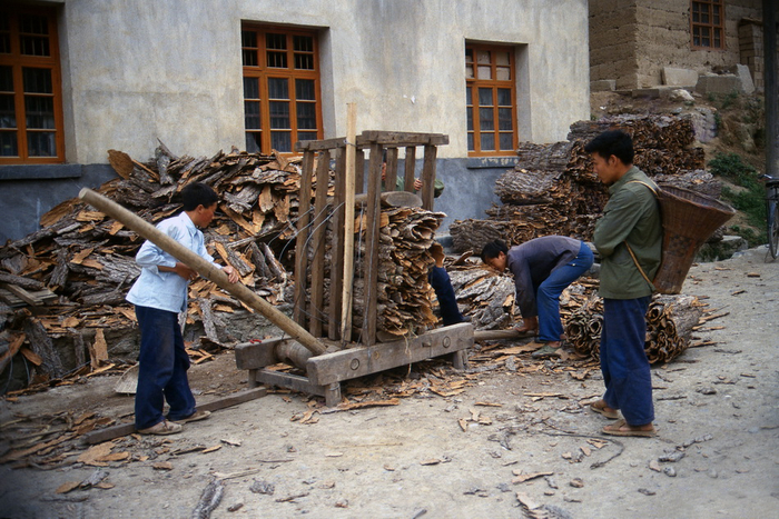 1989年，湖北长阳，某供销社工人用自制的土机械压捆树皮。