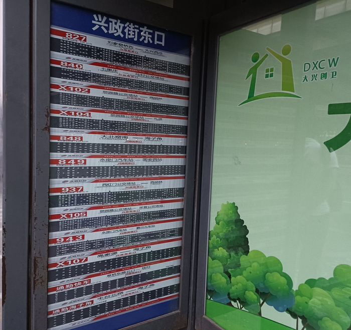 兴政街东口公交站的三个站牌，每个站牌上都标注着12条公交车的线路信息。王青供图