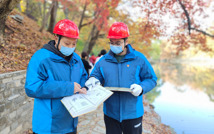 杜劲松（左）和年轻人交流树木修剪经验。颐和园供图