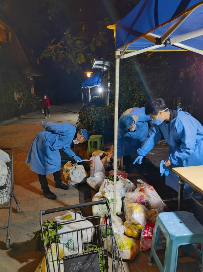 ▲夜幕下，志愿者还在核对菜品，确保居民的生活物资送到家