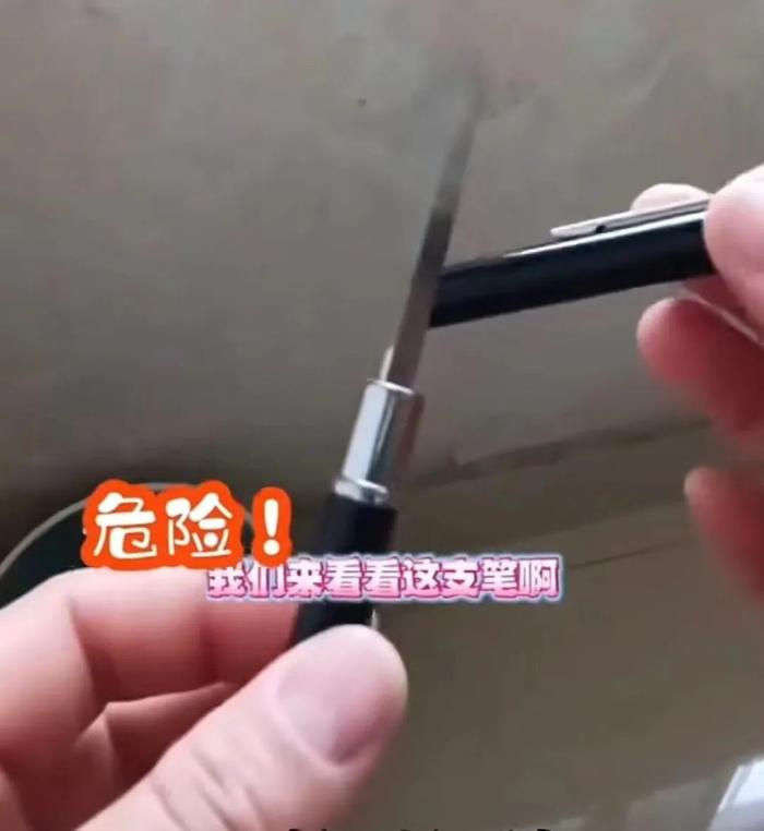 ▲河南一位学生家长展示从校门口买到的圆珠笔,打开笔帽露出的竟是一把刀。截图来自社交媒体视频