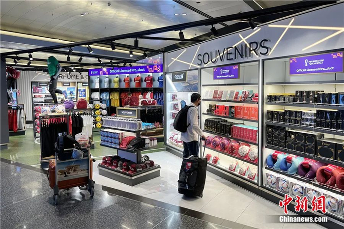 旅客在哈马德国际机场内的2022年世界杯纪念品商店中挑选纪念品。图片来源：中国新闻网