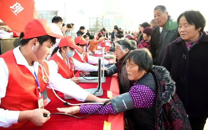 志愿者在安徽亳州市魏武广场为市民义务测量血压。图片来源：新华社
