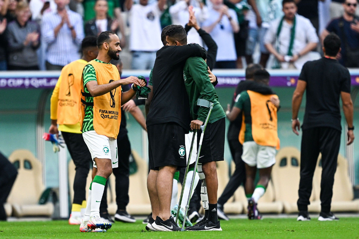 沙特队长萨尔曼-法拉吉赛后拄拐拥抱队友与教练