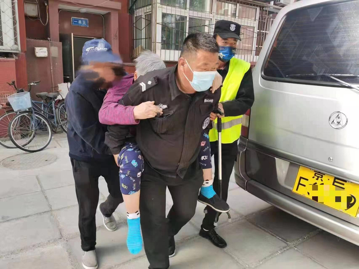 北京航天科工云岗项目的物业人员背着老人下楼，并协助老人就医。受访者供图