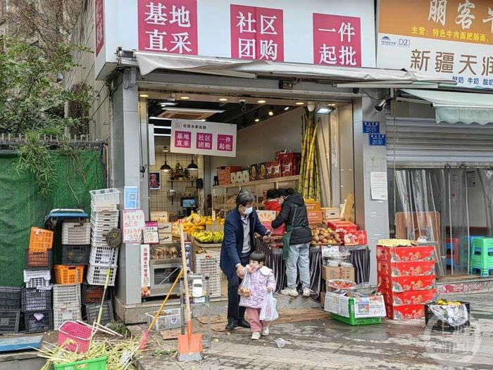 ▲12月2日中午，一位老人带着孩子走出小区购买水果。上游新闻记者 陈竹