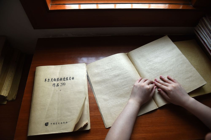 　　↑王香君在位于安徽淮南的家中学习钢琴琴谱（2015年7月13日摄）。