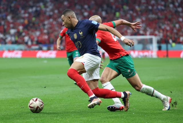 12月14日，法国队球员姆巴佩（左）与摩洛哥队球员索夫扬·阿姆拉巴特在比赛中拼抢。新华社记者 曹灿 摄