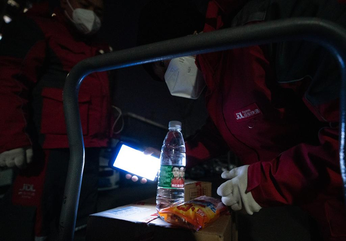 在北京市大兴区新源时代小区，一位居民给快递小哥送来水和火腿肠（12月15日摄）。新华社记者陈钟昊 摄