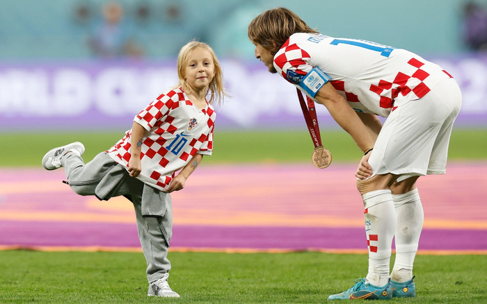 戴上奖牌与孩子互动，莫德里奇以赢家身份告别卡塔尔。  图/新华社