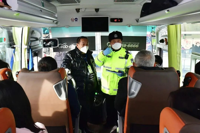 交警对长途客车内乘客进行安全带检查和提示/何建良摄