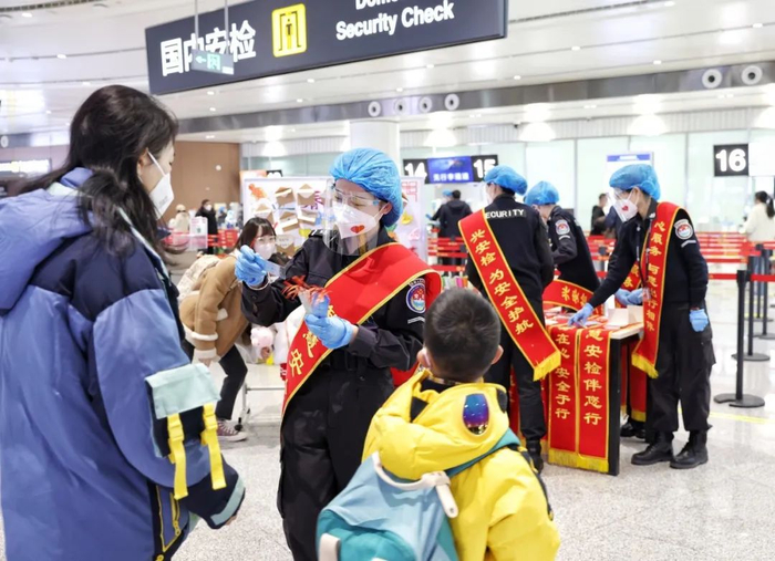 ▲机场安检区，安检人员为旅客发放有安检法规宣传内容的书签。