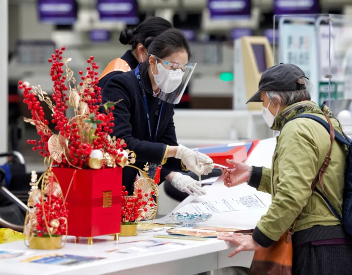 ▲机场候机楼咨询柜台前，工作人员为旅客提供服务。