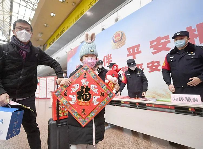 ▲小朋友展示民警叔叔送的春节福字和兔子玩偶。