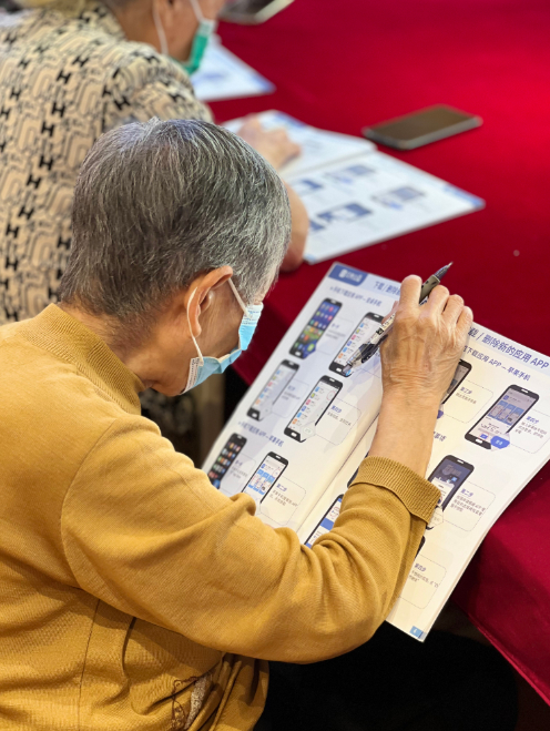 社区老年居民仔细阅读“我来教您用手机”课本