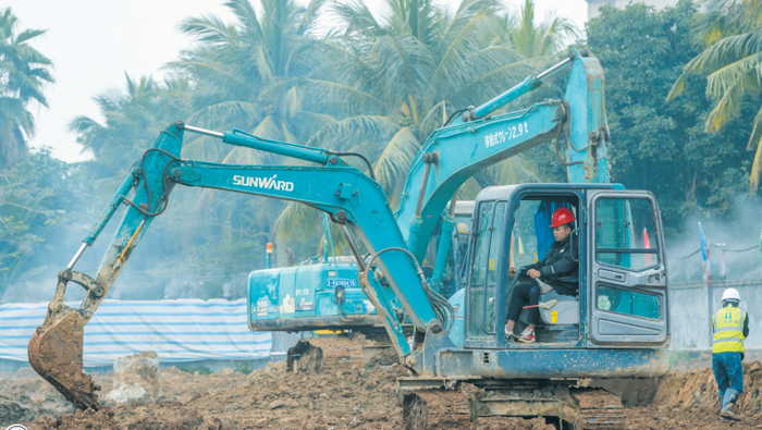 海口市职工活动中心项目工地现场，一派热火朝天的施工场景。工人正驾驶挖掘机开展作业。康登淋 摄