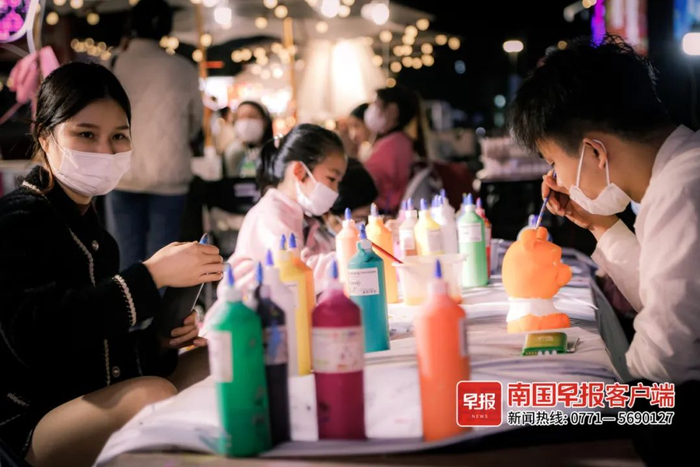 ▲江南万达广场门外，市民在摊点前涂鸦。