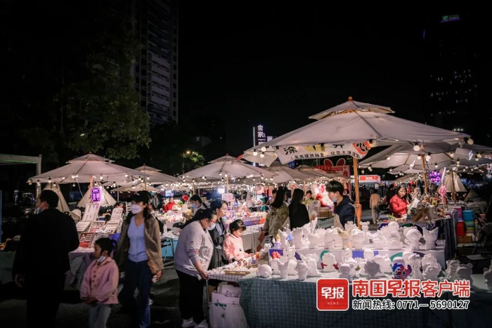 ▲江南万达广场门外有多家摊点，市民带孩子闲逛。