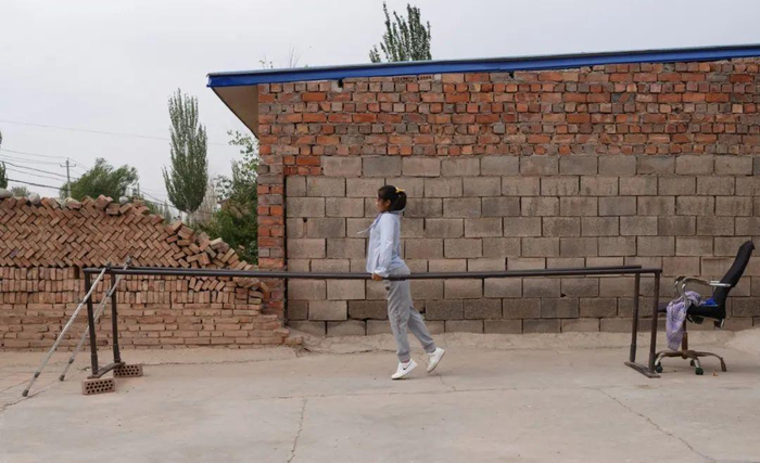 23岁的李兴兰正在自家院子里设置的双杠中进行康复训练。新京报记者 陈杰 摄