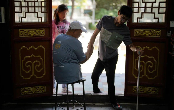 王辉在店门口扶着22岁的员工贾君健进门。新京报记者 陈杰 摄