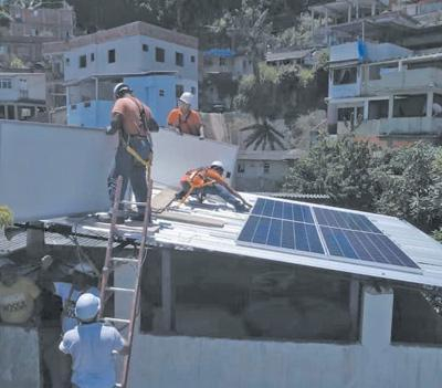 光伏设备安装技术员在巴西里约热内卢市一处居民楼上工作。罗德尼·梅略摄