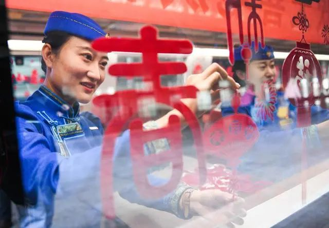 1月14日，G2457次复兴号列车到达呼和浩特东站之后，乘务人员整理窗花，准备迎接下一批旅客。新华社记者 刘磊 摄