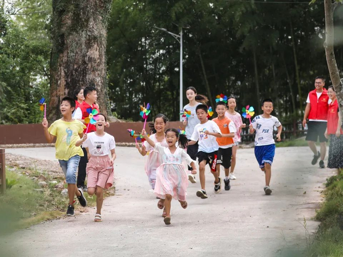 2022年8月17日，江西省宜春市上高县野市乡水口村，大学生志愿者正与留守儿童一起玩大风车游戏。通讯员 陈旗海 摄
