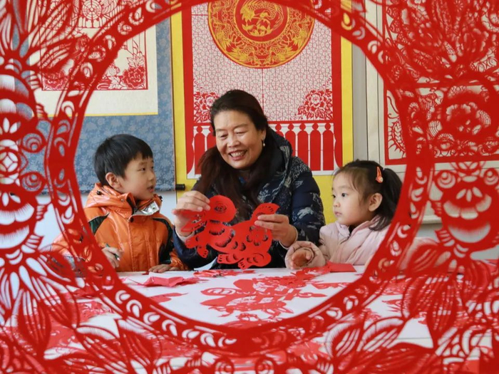 2022年12月30日，在山东省高密市剪纸艺社，非遗传承人田桂芹在带领孩子们进行迎新年剪纸创作。通讯员 李海涛 摄
