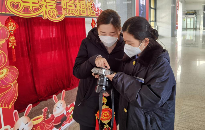 　　王雪冰（图右）在和旅客挑选照片。（中国铁路上海局集团有限公司淮南西站供图）