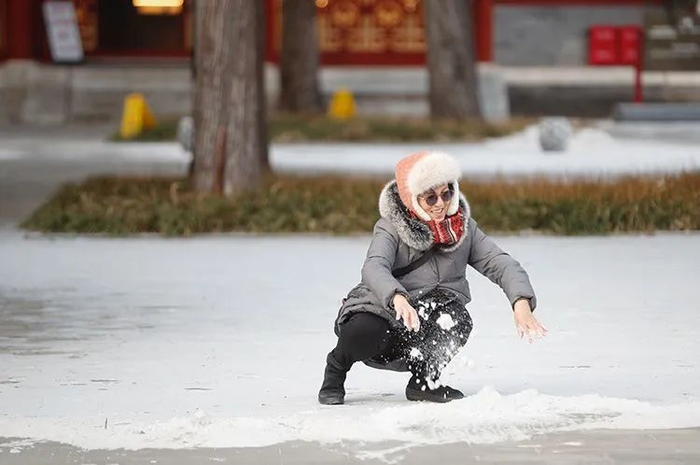 ▲景山公园寿皇殿景区，游客触摸兔年第一场雪