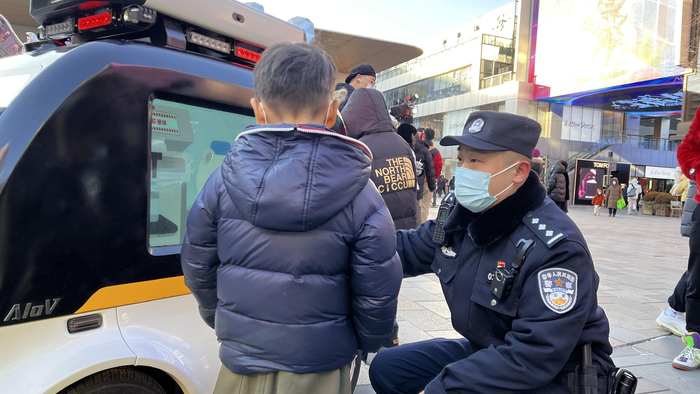 民警正在向路过的小朋友讲解反诈宣传机器人的用途。北京市公安局朝阳分局供图