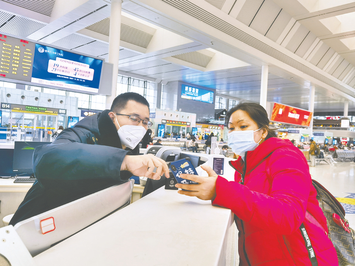     ▶ 钟昊志在南宁东站“刘三姐·南宁东”服务台回答乘客的问题。    （林孟婕 摄）