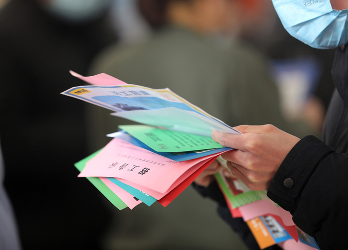 2023年1月29日，河南安阳，一名求职者在企业用工招聘会上收集到的招聘岗位信息。