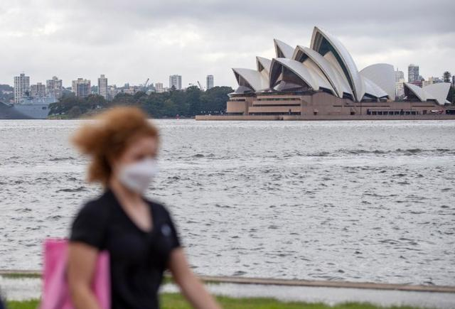 2022年3月30日，在澳大利亚悉尼歌剧院对岸，一名女子佩戴口罩出行。新华社记者白雪飞摄