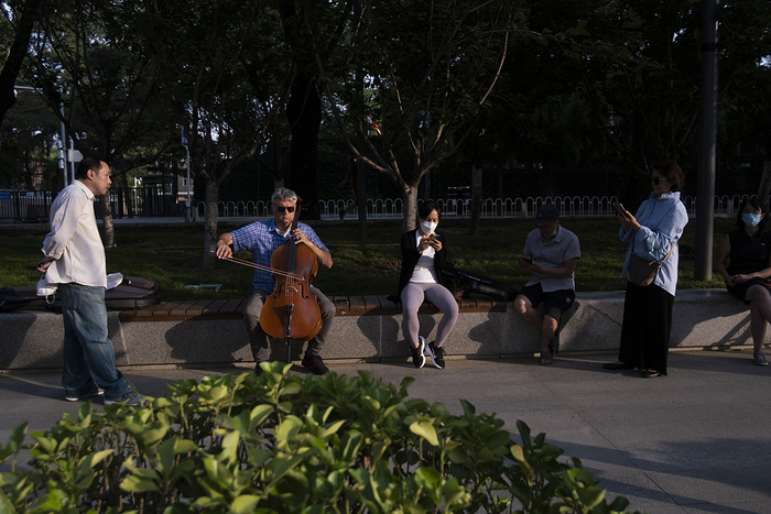 2022年6月14日，一位外国音乐人在三里屯亮马河边拉大提琴，吸引行人驻足。潘松刚 图
