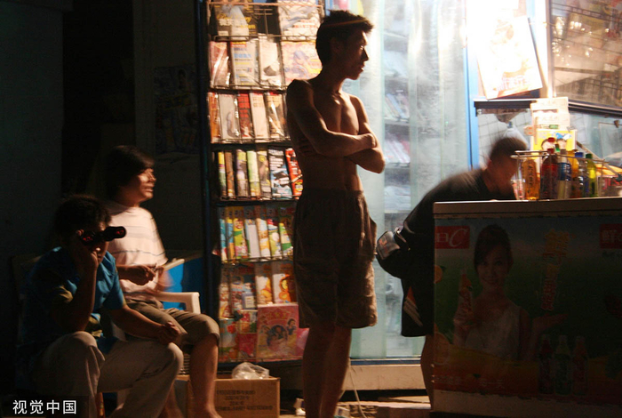 2007年6月18日，北京三里屯酒吧街对面，一位年轻人用望远镜看酒吧里的表演。