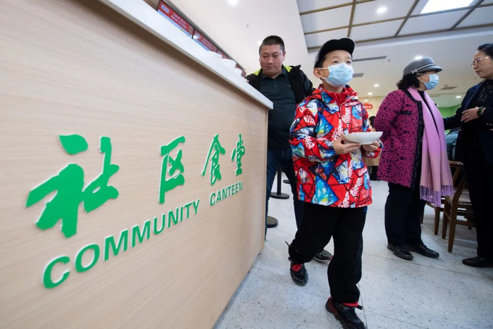 一名小朋友在社区食堂端菜 杨晨光 摄