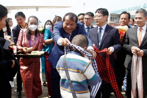 2月7日，柬埔寨旅游大臣童昆（中）在金边国际机场为中国旅客带上该国传统的高棉围巾。新华社发（批隆摄）