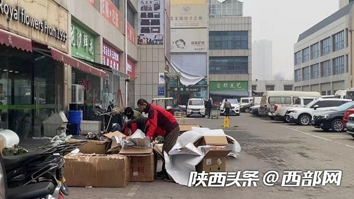 商铺门外，店家工作人员在捆扎打包鲜花包裹。