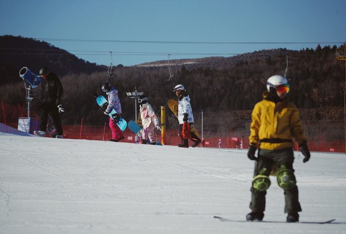 2022年12月28日，北京渔阳国际滑雪场，单板爱好者走向雪道出发点。资料图片/新京报记者 薛珺 摄