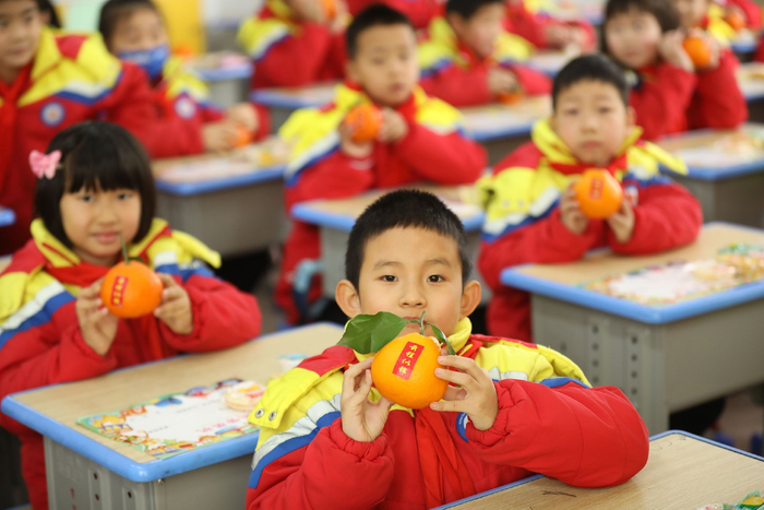 2023年2月7日，山东日照，学校老师们分发贴有祝福语的橙子，欢迎学生们回家。视觉中国 图